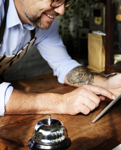 Tattooed man using digital tablet in baker's shop